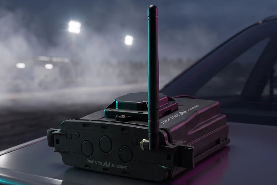 The DRIFT/RS AI Judging box on the boot of a car at night: a black case lettered DRIFT/RS AI JUDGING, the flat GNSS antenna on its lid and its Wi-Fi stick antenna